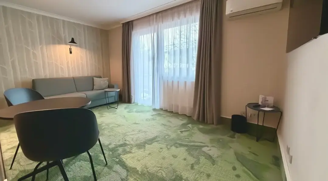 Helles Zimmer mit grüner Teppichboden.