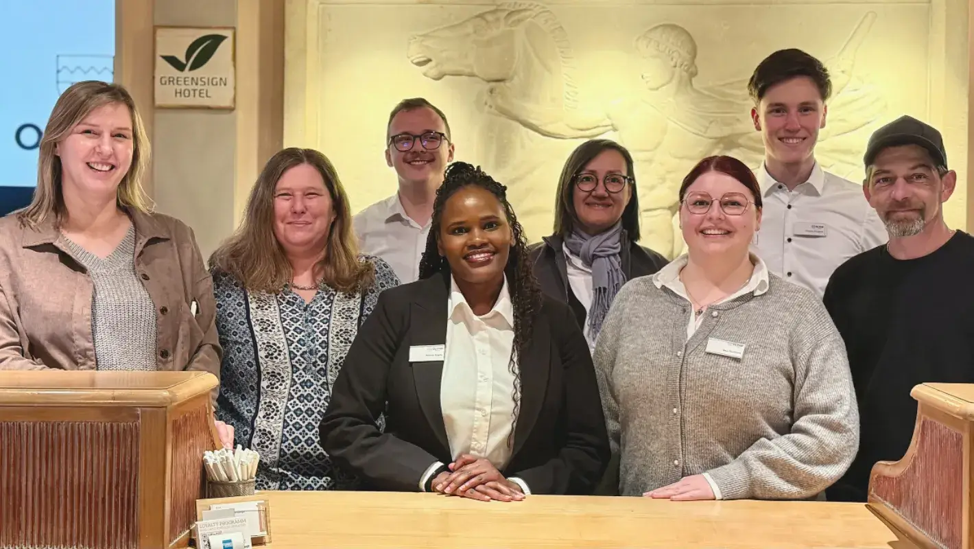 Hotelteam am Empfang, lächelnd.
